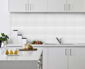 White Subway tile backsplash installed on the wall of a kitchen with grey wooden cabinets and white stone countertop.