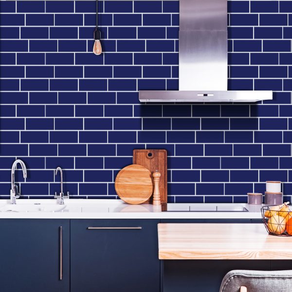Blue Subway tile backsplash installed on the wall of a kitchen with blue wooden cabinets and white stone countertop.