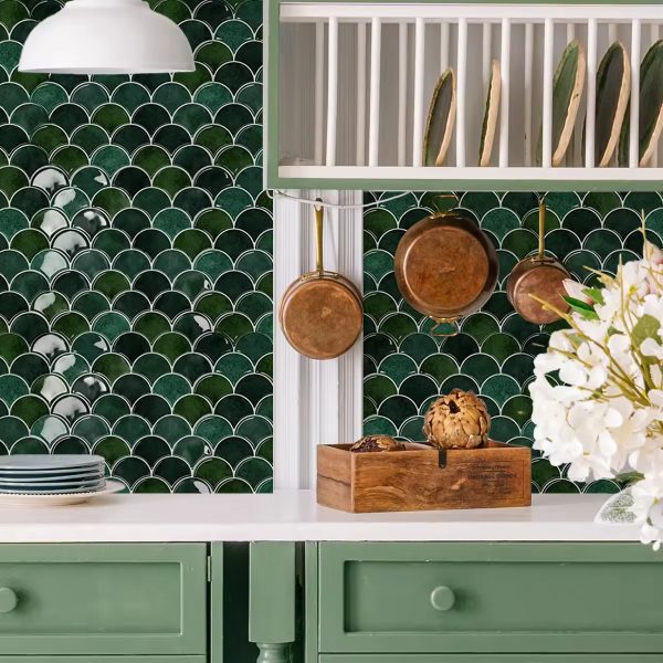 Green Fish Scale tile backsplash installed on the wall of a kitchen with grey wooden cabinets and white stone countertop.