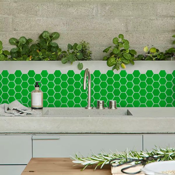 Green Hexagon tile backsplash installed on the wall of a kitchen with grey wooden cabinets and cement countertop.